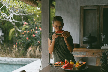 A young woman eats a ripe watermelon.