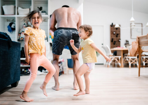 Sisters Having A Dance Party In Kitchen With Dad