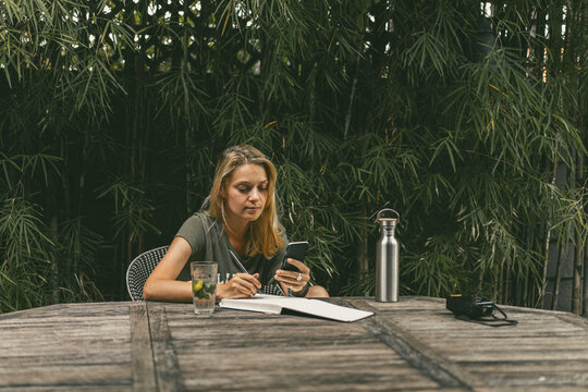 A young woman writes plans, takes a selfie, work as a blogger.