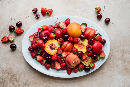 Top view of large plate of mixed fruit: berries, peaches, cherries. - Powered by Adobe