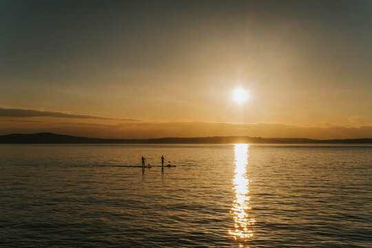 Paddle boarders on Alki Beach at sunset Puget Sound