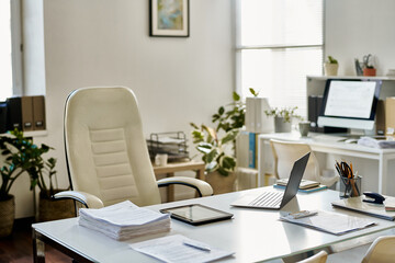 Workplace of manager with laptop and stack of documents on table in office