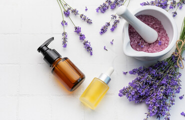 Lavender spa. Lavender salt, natural essential oil and fresh lavender on a white tile background.