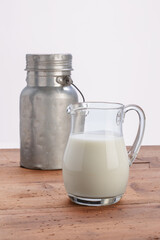 glass jug full of milk with aluminum milk jug on wooden rustic table