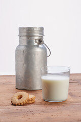 full glass cup of milk with aluminum milk jug on wooden rustic table.