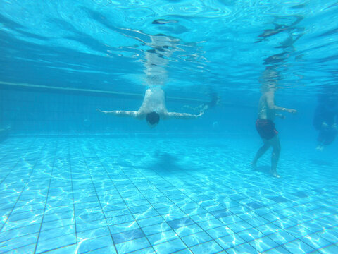 Underwater photo of people diving and swimming in the pool.