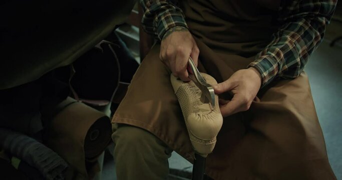 Young bootmaker drive in nails in a shoe at the private workshop. 