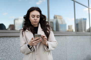 Fototapeta premium young brunette woman freelancer communicates in social networks on the phone on the street