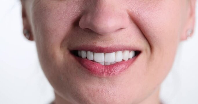 Woman smiles widely with white teeth on white background. Female person shows perfectly maintained oral cavity. Concept of treatment at dentist and regular checkups