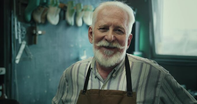 Portrait of a joyful mature male shoemaker looking at the camera and smiling. 