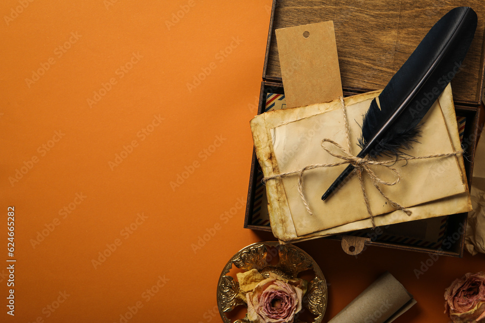 Wall mural wooden box with old letters and feather on orange background, space for text