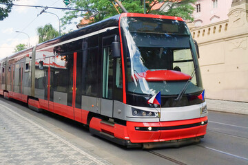 Fototapeta na wymiar Modern Tram in old stree of Prague in a summer day, Czech Republic. The Prague tram network is the third largest in the world. Passenger Eco-friendly electric transport connection in the Europe City