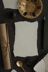 Papers, golden plates and spoon, ink bottle and pen on dark gray background, top view