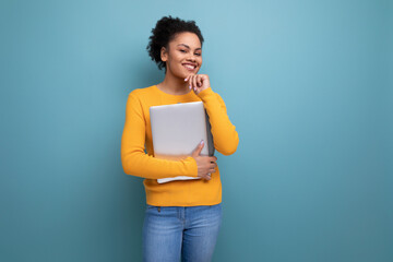 pretty young brunette latin female adult in yellow sweater holding a laptop in her hands