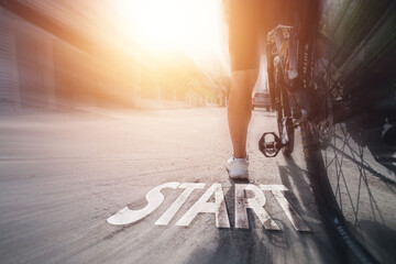Cyclist with text START running on road at sunset, concept to start something new

