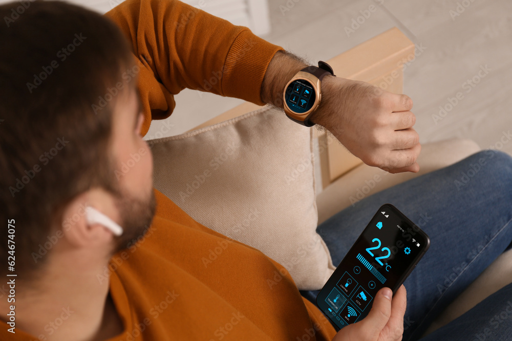 Poster man setting smart home control system via smartwatch and mobile phone indoors. app interface with ic
