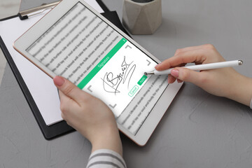 Electronic signature. Woman using stylus and tablet at table, closeup