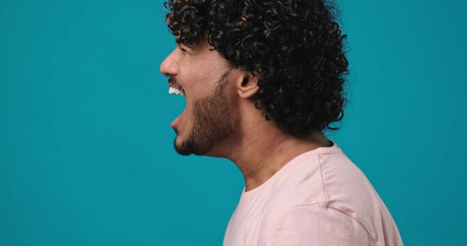 Handsome indian man scream yell close up profile side view standing isolated on blue studio background