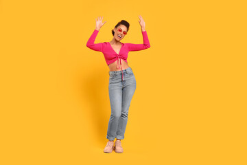 Fototapeta na wymiar Happy young woman in stylish sunglasses dancing on orange background