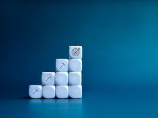 Goal target icon and arrows on white blocks business chart steps on blue background with copy space. The business growth graph process, goal, success, and economic improvement and analysis concepts.