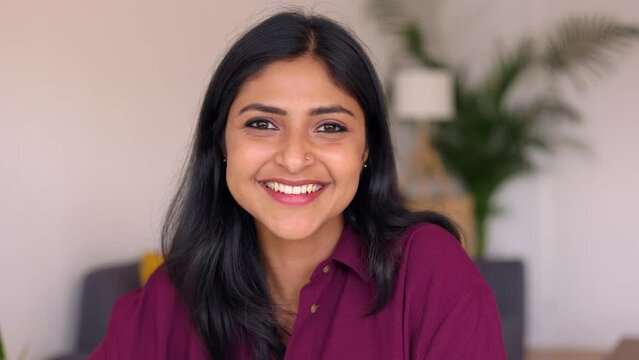 Happy young indian woman smiling at camera sit in the living room at home, webcam view. Cheerful portrait of millennial female native of India with toothy smile. Real people concept.