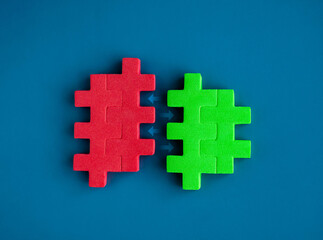 Red and green puzzle blocks between arrows are joining each other on blue background, minimal style. Business partnership, teamwork, collaboration, and contrast opposite colors concepts.