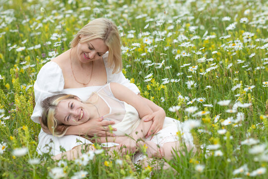 Family on nature on a summer sunny day. Mom with daughter in a chamomile field. Mom with daughter in white dresses. Image with selective focus.