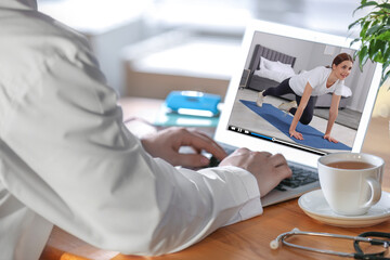 Man watching morning exercise video on laptop at home, closeup