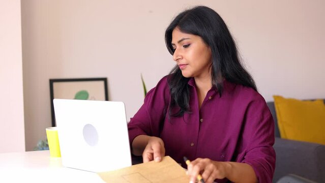 Young indian woman working on laptop. Concentrated businesswoman looking at computer screen reading some job article or listening at virtual video call training class