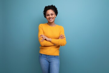 pretty 20s latin woman with afro hair in casual yellow blouse posing on studio background