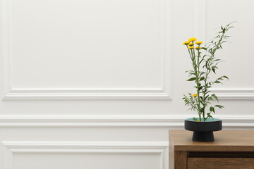 Ikebana art. Beautiful yellow flowers and green branch carrying cozy atmosphere at home, space for text