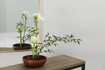 Stylish ikebana with beautiful flowers and green branch carrying cozy atmosphere at home