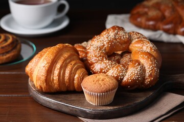 Different tasty freshly baked pastries on wooden table, closeup