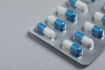 Pills in blisters on grey background, closeup. Space for text
