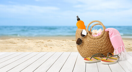 Obraz premium Summer vacation. Bag with sunscreen and accessories on sunny ocean beach, space for text. Banner design