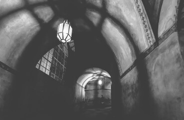 light from the lamp and the shadows in the mysterious corridor in the old dungeon in the castle, black and white