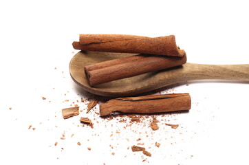 Cinnamon sticks, pieces with shavings in wooden spoon isolated on white 
