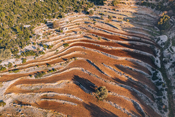 A captivating aerial view showcases the patchwork of a plowed field adorned with terraces, a...
