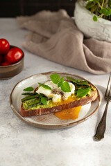 Toasted sourdough bread with grilled asparagus, avocado, poached egg and herbs for single serving. Avocado toast. Breakfast idea. Healthy food concept.