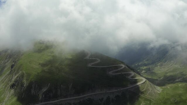Beautiful roads of Romania. 4K aerial video with Transalpina road on top of the mountains with big clouds above. Curved waving road.