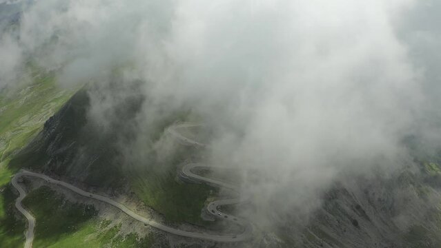 Beautiful roads of Romania. 4K aerial video with Transalpina road on top of the mountains with big clouds above. Curved waving road.