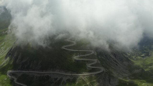 Beautiful roads of Romania. 4K aerial video with Transalpina road on top of the mountains with big clouds above. Curved waving road.