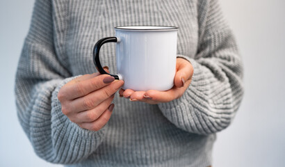 Person holding mug with hot beverage in hands. Girl with rustic cup in winter time