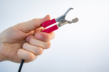 Crocodile alligator clip in guy hand for electrical and electronic testing connect solder. Person measuring of tension and voltage