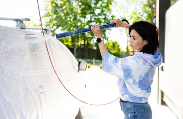 Girl washing a car in a self-service car wash station. Wash car self-service station.