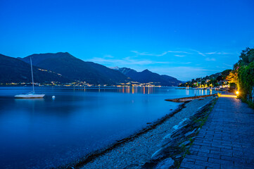 Il paese di Pianello del lario, sul lago di Como, e la passeggiata lungo il lago, all'imbrunire. Alpi, montagne e paesi del lago in lontananza.
