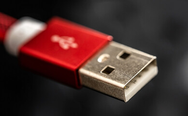 Red USB connector for smartphone and gadgets closeup on black background. Plug cable for mobile devices in macro
