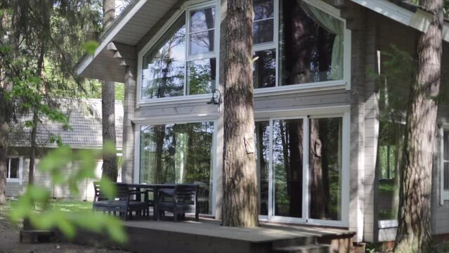 Country house made of wood with large panoramic and open veranda in summer in a pine forest