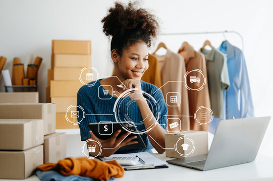  African Woman using a laptop, smartphone and tablet and writing notebook at the modern office of her business online shopping. In home with virtual icon