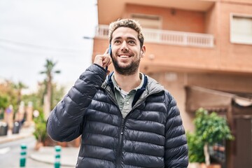 Young man smiling confident talking on the smartphone at street